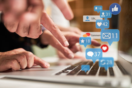 Finger typing on keyboard on laptop computer with many news icons as social media concept