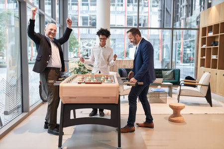 Businessman wins playing table football at the foosball table in the office and cheers