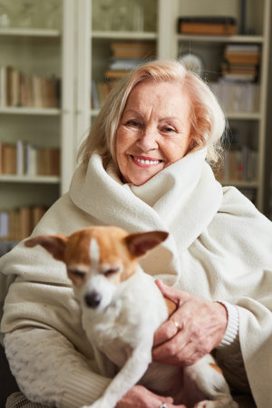 Happy old woman with scarf and small dog on her lap for companionship and against lonelinessの写真素材