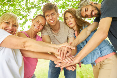 Group of friends stacks hands for motivation outdoors in nature