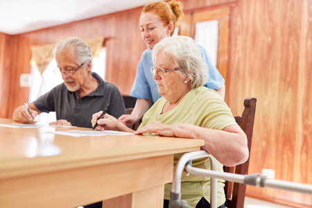 Couple of seniors sitting at table in nursing home and solving puzzles as memory training against dementiaの写真素材