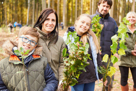 Family and children as volunteers with tree seedlings for sustainable reforestationの写真素材