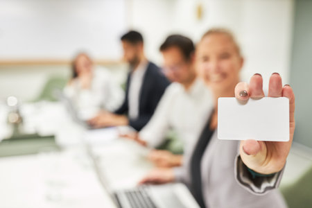 Young businesswoman holding credit card or business card in hand in a computer courseの写真素材
