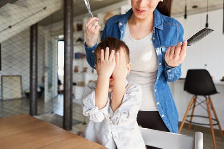 Child holds his hands in front of his face for fear of cutting his hair at the hairdresserの写真素材