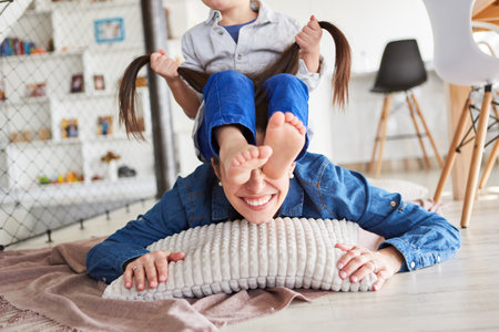 Little boy fools around on his mother's back and pulls her long hairの写真素材