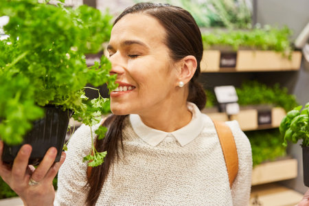 Young woman as a customer smells fresh herbs in the food department in the supermarketの写真素材