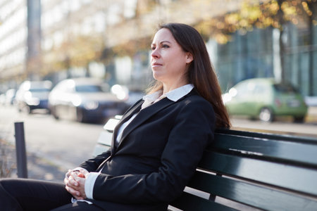 Businesswoman taking a break while sitting on park bench in cityの写真素材
