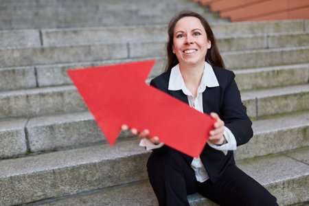 Confident businesswoman holding red arrow symbol as career and success sign