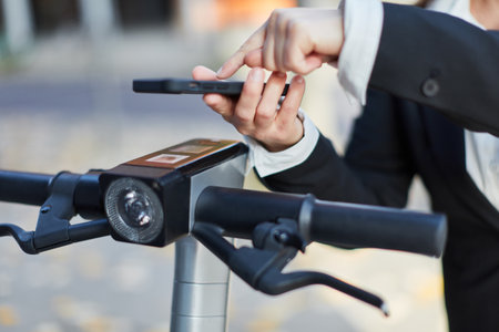 Hand of businesswoman renting e-scooter with smartphone in the streetsの写真素材