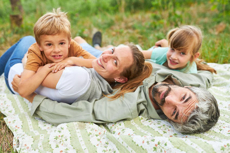 Portrait of smiling family lying on blanket at campsite during summer holidayの写真素材