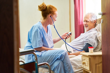 Nurse or caregiver measuring blood pressure of senior in bed in home care