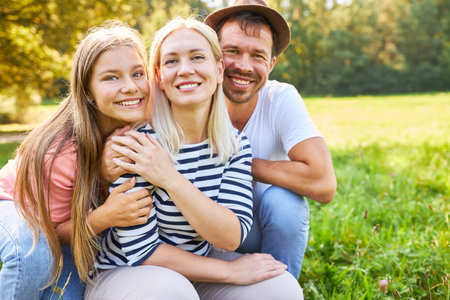 Happy family with parents and daughter on a meadow in the park in nature