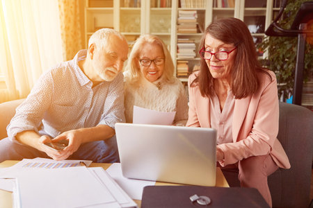 Couple of seniors having advice on insurance and pensions at home with consultant on laptop computer