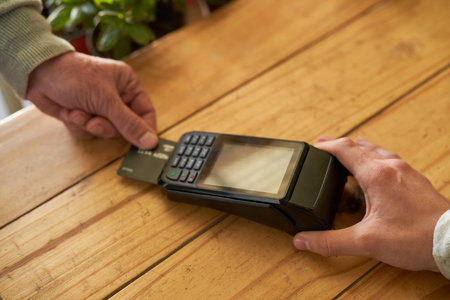 Hand puts credit card in the reader at the checkout for cashless payment in retailの写真素材