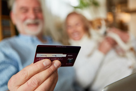 A senior's hand holds a credit card for cashless payment and for e-commerce in online retailの写真素材