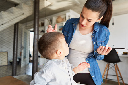Boy discussing haircut in hair salon with his mother or a hairdresser