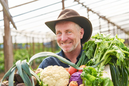 Portrait of happy male farmer with crate of fresh vegetables at farmの写真素材