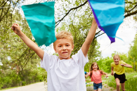 Portrait of smiling boy reaching finish line with male and female friends in background at parkの写真素材
