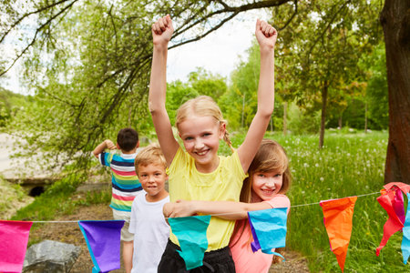 Portrait of girl cheering with male and female friends after winning race competition during summerの写真素材