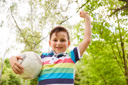 Portrait of male winner celebrating success after soccer game at garden during summer holidayの写真素材
