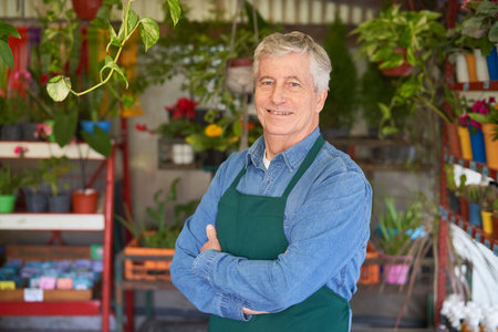 Smiling gardener or florist as boss in his flower shop with arms crossedの写真素材