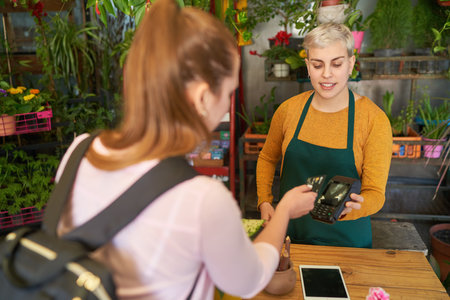 Customer in the flower shop at the checkout makes mobile payment with a credit card on the NFC readerの写真素材