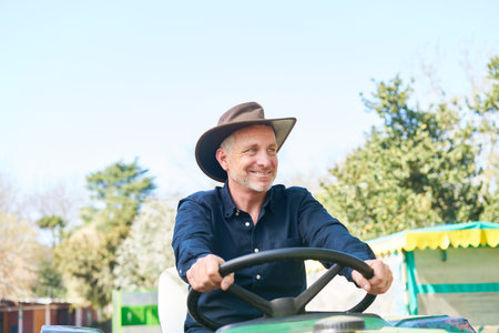 Happy farmer driving tractor on farm in summerの写真素材