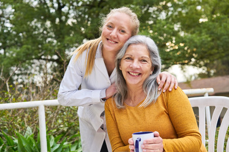Portrait of happy female doctor with senior woman in garden of nursing home