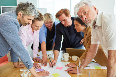 Senior businessman in meeting with colleagues discussing documentsの写真素材