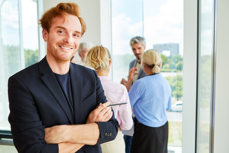 Portrait of smiling redhead businessman standing with arms crossedの写真素材