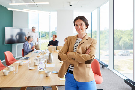 Smiling female professional wearing blazer with arms crossedの写真素材