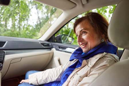 Smiling senior woman wearing jacket sitting in car during road trip