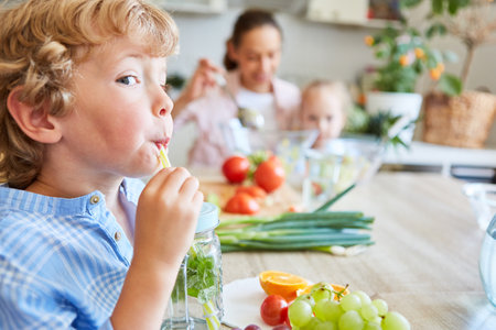 Playful blond boy sipping detox water from mason jar in kitchen at homeの写真素材