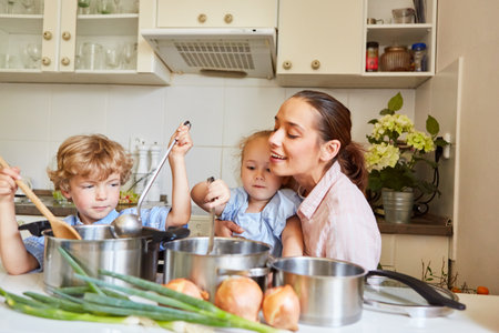 Son and daughter making soup with mother in kitchen at homeの写真素材