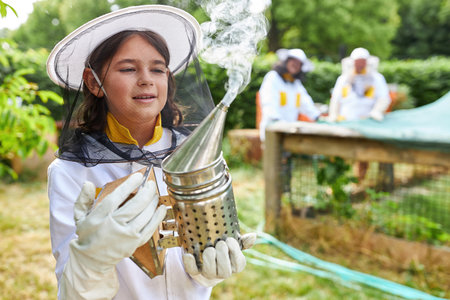 Girl as beekeeper with bee smoker in front of bee hives in the gardenの写真素材