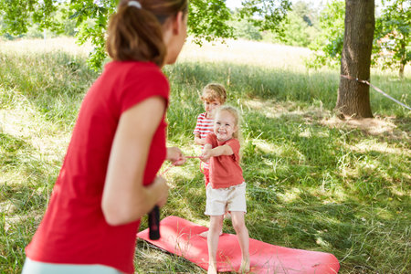 Happy girl playing with mother using skipping rope while standing in garden