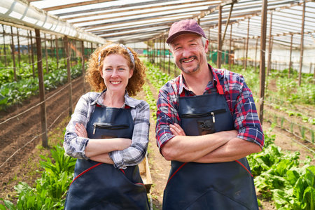 Portrait of smiling mature male and female farmers standing with arms crossed in farmの写真素材