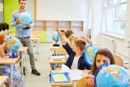 Elementary school teacher with a globe teaching class of children in geographyの写真素材