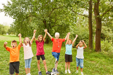 Cheerful male and female friends holding hands while celebrating at parkの写真素材