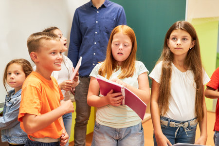 Schoolgirl reading book while standing with classmates at schoolの写真素材