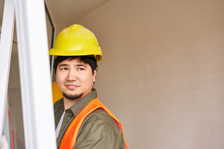 Young male construction worker carrying window frame