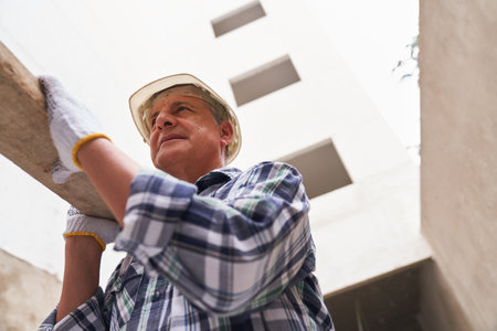 Senior male worker carrying planks