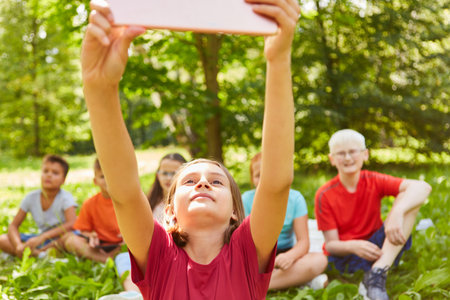 Girl taking selfie with friends through tablet PC at parkの写真素材