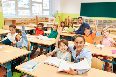 Portrait of elementary school teacher sitting with school children in classroomの写真素材