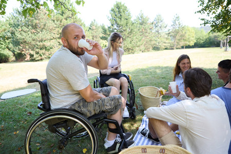 Inclusive outdoor picnic scene showing people with and without disabilities enjoying a sunny day...