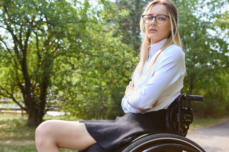 A confident woman who uses a wheelchair is portrayed enjoying a sunny day outdoors, promoting inclusivity and empowerment.の写真素材