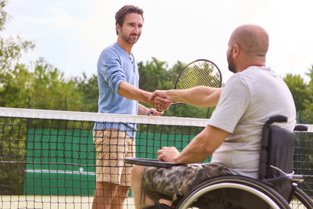 An image capturing a warm moment of sportsmanship as a man using a wheelchair and his opponent shake...