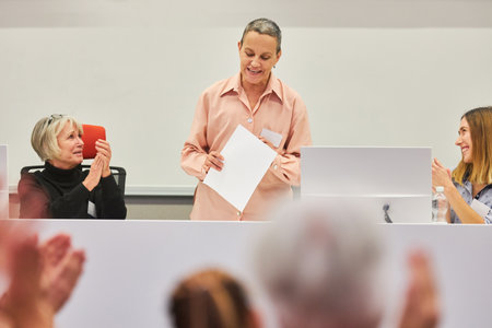 Female speakers applauding at conference in front of audience at business event