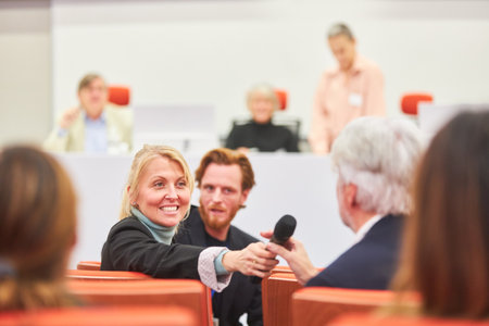 Smiling female professional asking question to businessman during conference in convention centerの写真素材