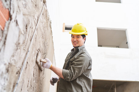 Smiling male labor applying cement on wall